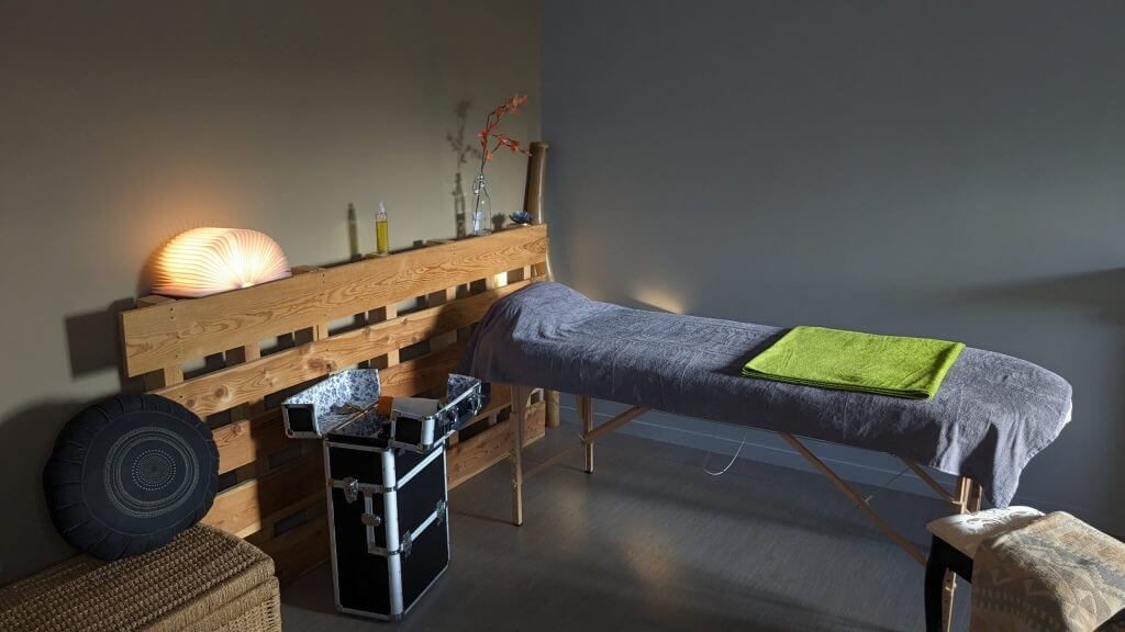 Salle de massage avec une table un siège et tout le matériel de massage